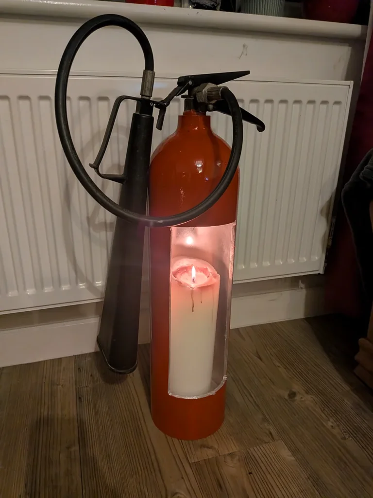 Angled front view of red fire extinguisher candle holder #3 showing the tall candle opening and original black fittings.