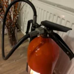 Close-up of the original black handle and hose connection on fire extinguisher candle holder #3.