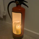 Angled front view of a red upcycled fire extinguisher candle holder with a black-trimmed opening.