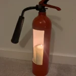 Angled view of fire extinguisher candle holder #8 showing the white-painted interior and candle opening.