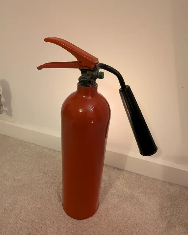 Rear view of upcycled red CO2 fire extinguisher candle holder #8 with its original handle and black discharge horn.