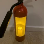 Detail of fire extinguisher candle holder #8 illuminated by a warm yellow LED candle inside the white-painted interior.