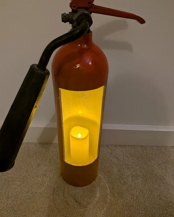 Detail of fire extinguisher candle holder #8 illuminated by a warm yellow LED candle inside the white-painted interior.