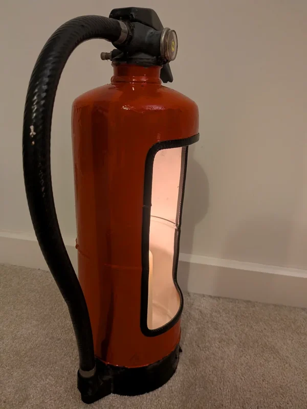Side view of upcycled fire extinguisher candle holder #9 showing the original hose, red body and illuminated opening.
