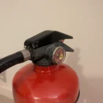 Close-up of the original handle and pressure gauge on red upcycled fire extinguisher candle holder #9.