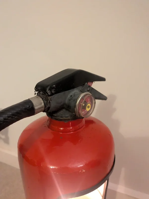 Close-up of the original handle and pressure gauge on red upcycled fire extinguisher candle holder #9.