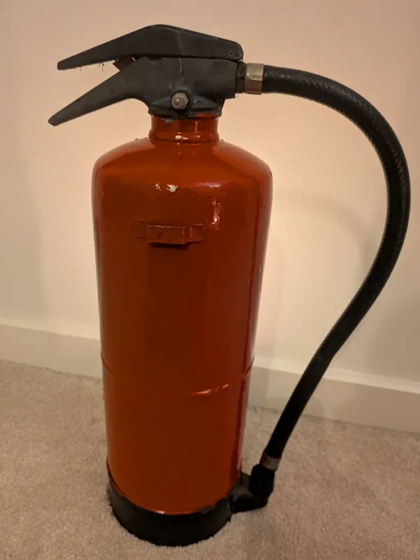 Rear view of red upcycled fire extinguisher candle holder #9 with its original black hose and handle.
