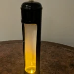 Close view of a black nitrous canister candle holder showing candlelight against the white-painted interior.
