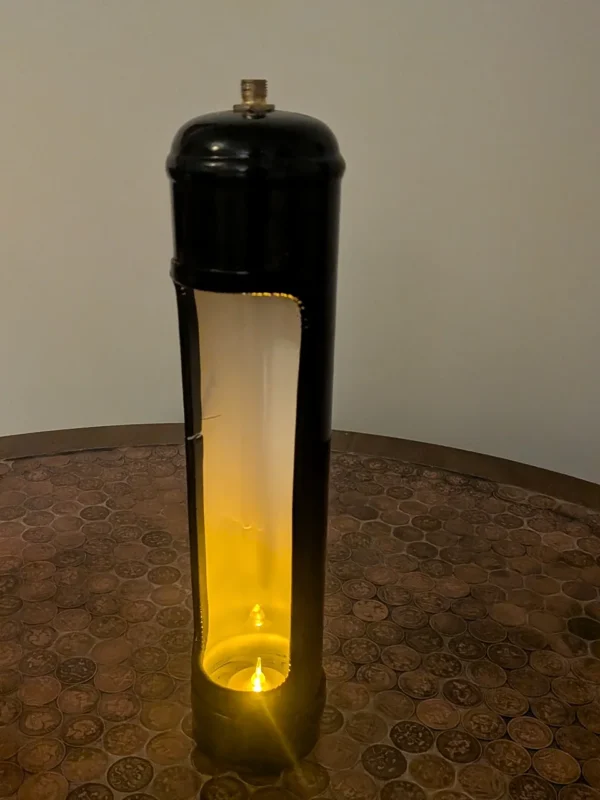 Close view of a black nitrous canister candle holder showing candlelight against the white-painted interior.